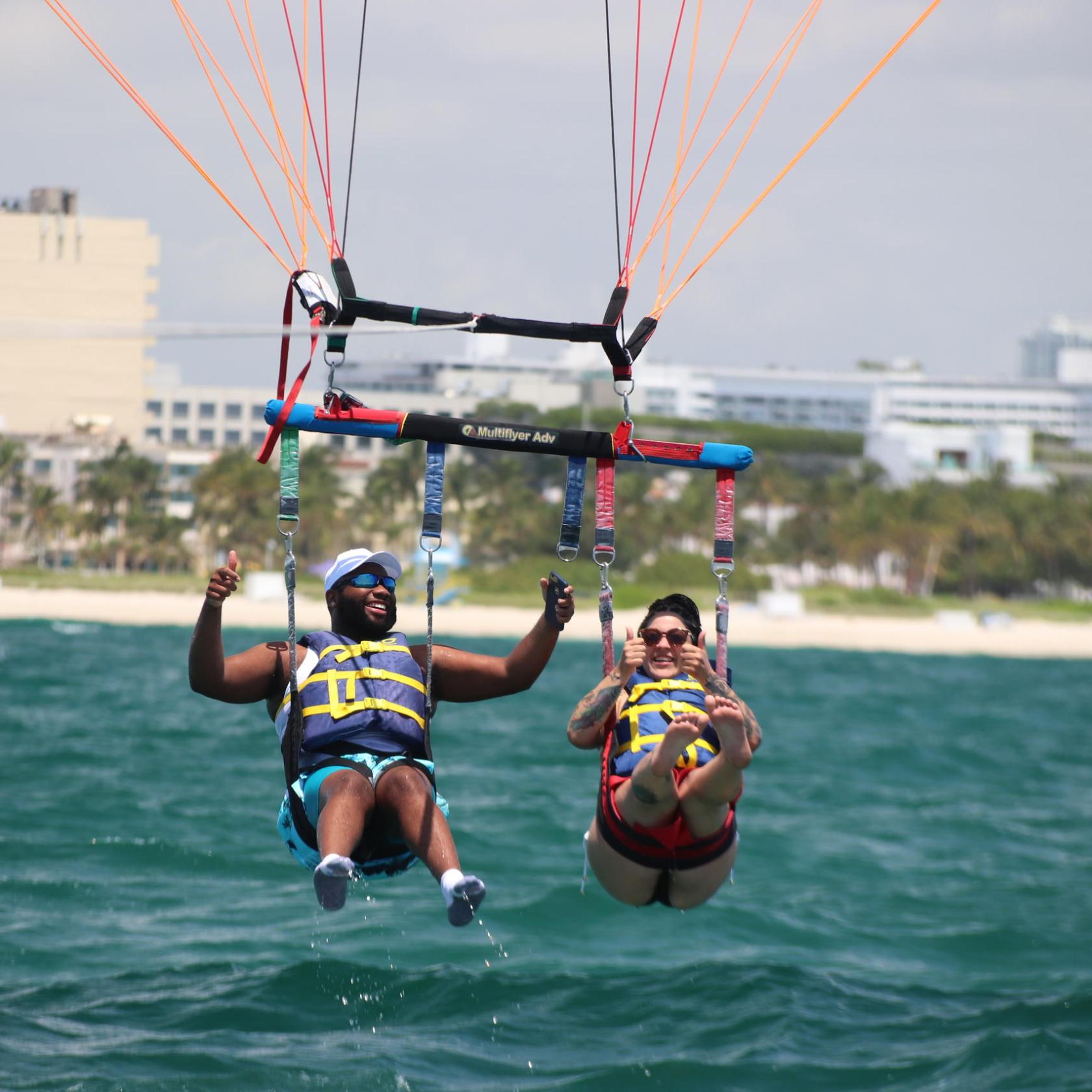 a group of people flying kites in a body of water